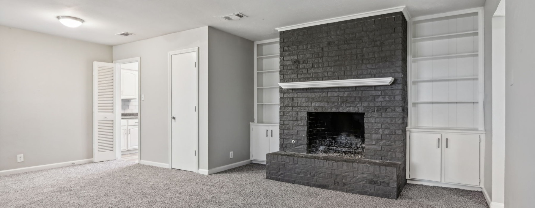 a room with a fireplace and white cabinets